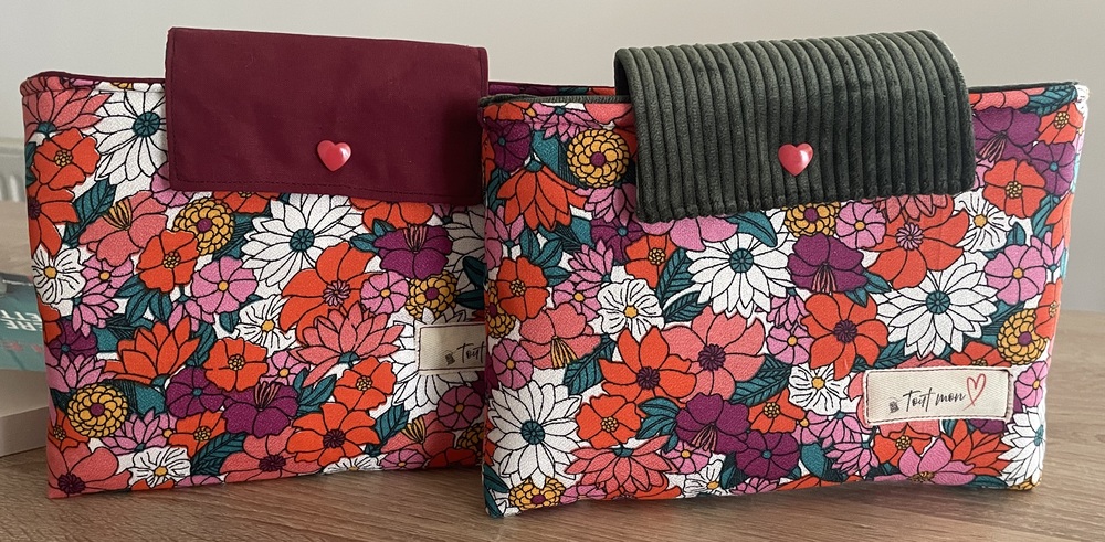 Deux pochettes à livre en tissu fleuri coloré à grandes fleurs rouges, roses et blanches : l'une avec rabat en velours bordeaux, l'autre avec rabat en velours kaki, chacune ornée d'un bouton cœur rouge